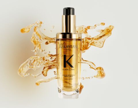 The new refillable Elixir Ultime is surrounded by beautiful golden hair oil drops and texture.